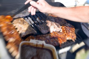 A man bastes meat on a barbecue grill